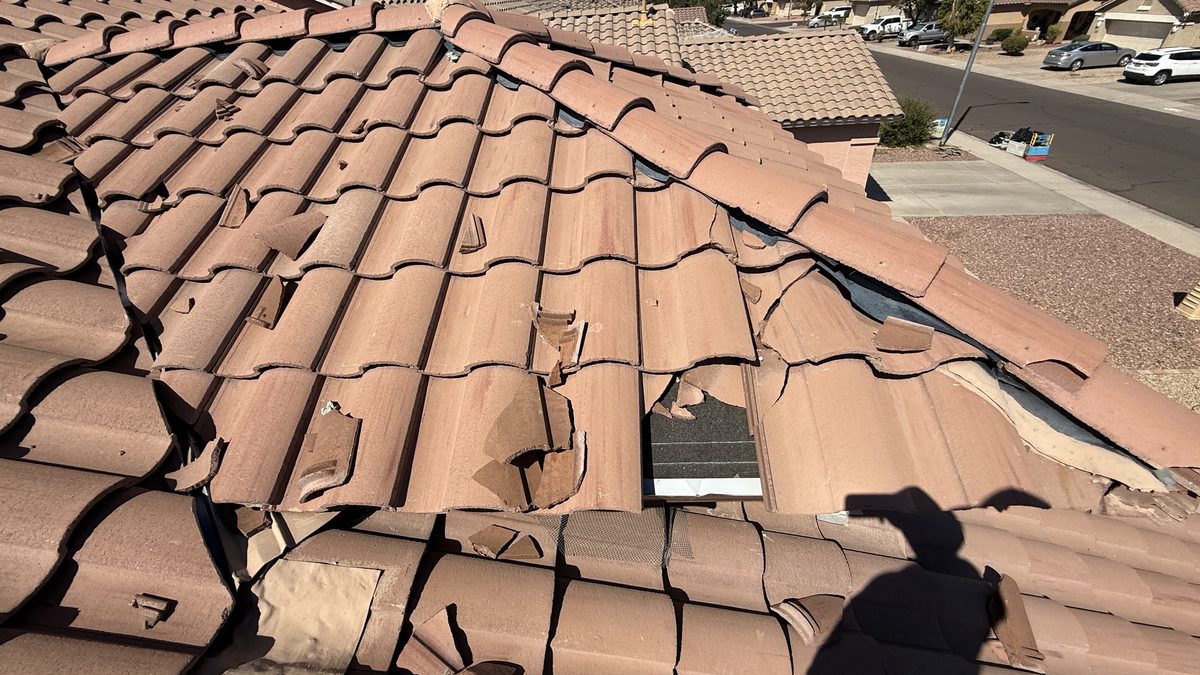 Broken roof tiles with exposed underlayment before repair