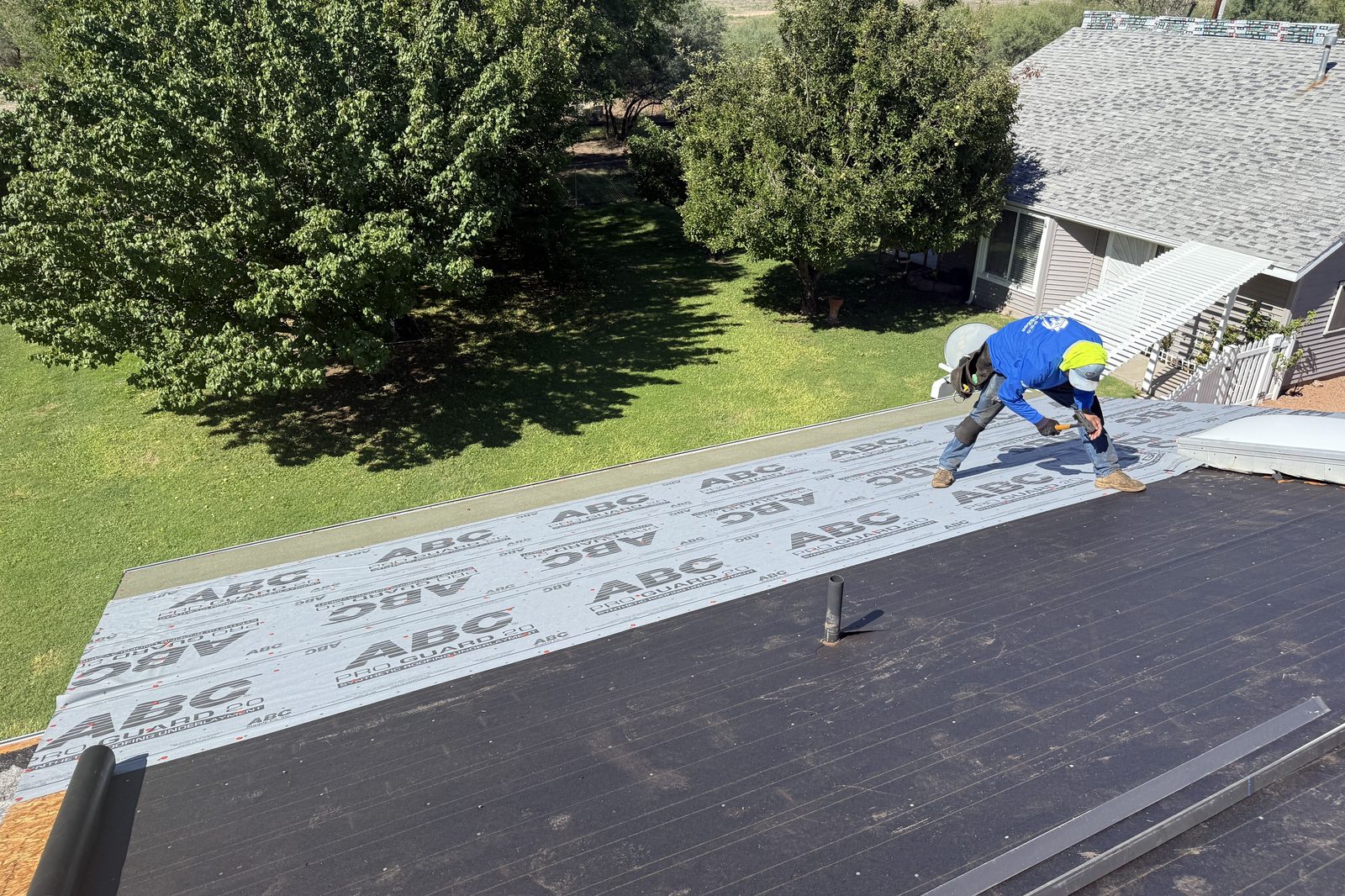 Installing underlayment Roofer installing synthetic underlayment during a roof replacement