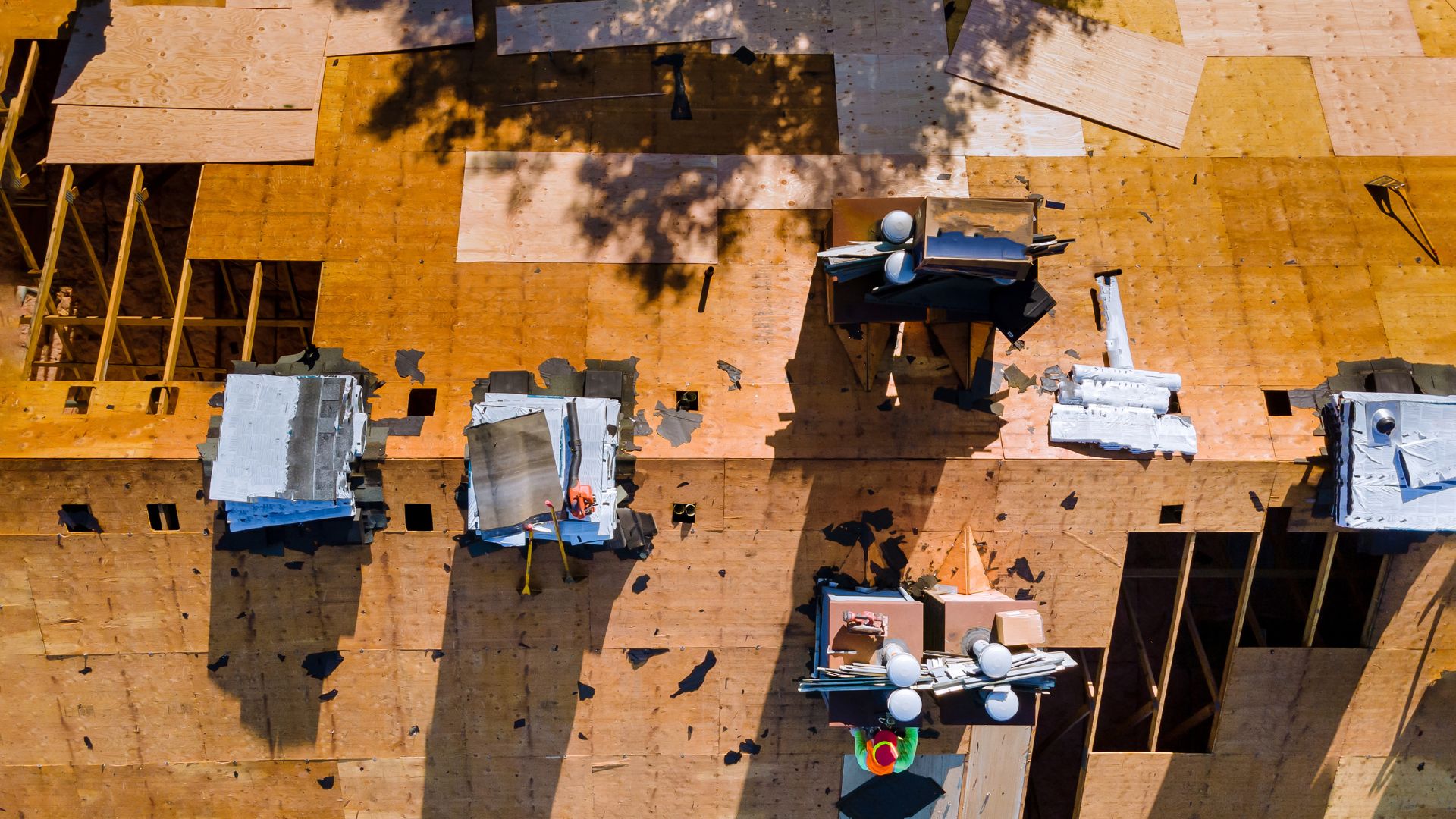 Workers on a bare roof deck installing a brand new full roof replacement.